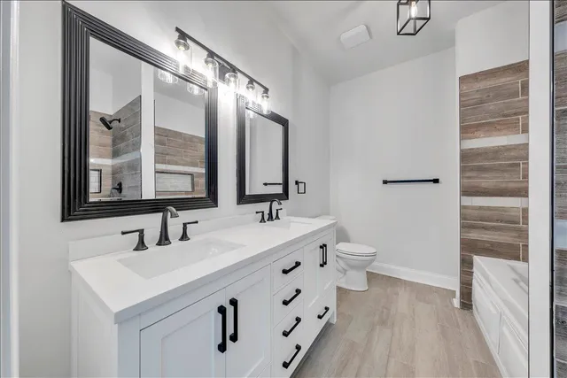 a bathroom with a double vanity sink a toilet and a mirror