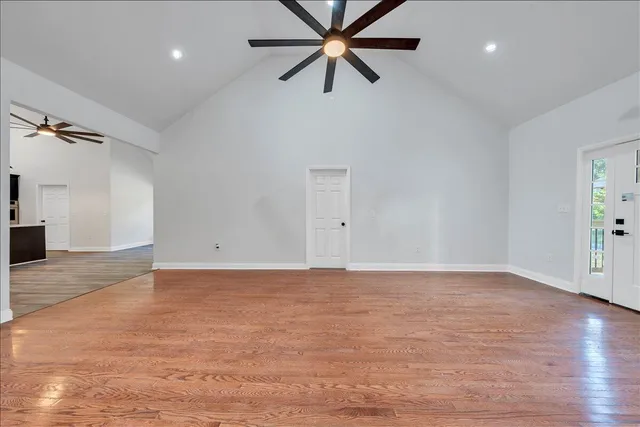 an empty room with wooden floor closet and windows