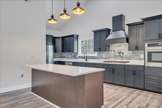 a kitchen with stainless steel appliances granite countertop a sink a stove and a wooden floors