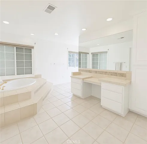 a spacious bathroom with a granite countertop sink mirror and bathtub