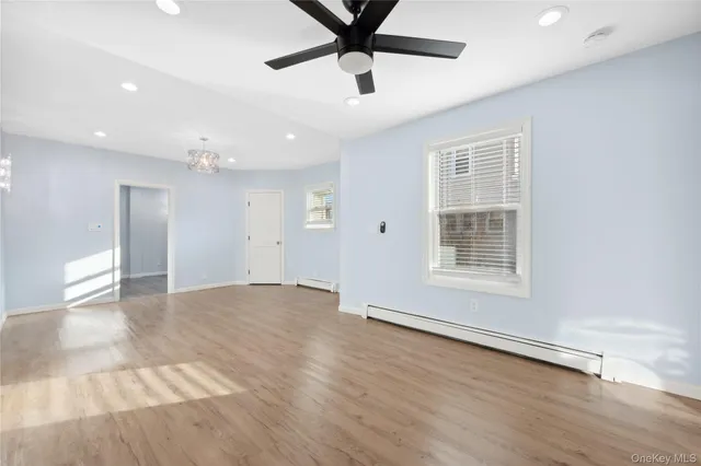 a view of an empty room with a window and wooden floor