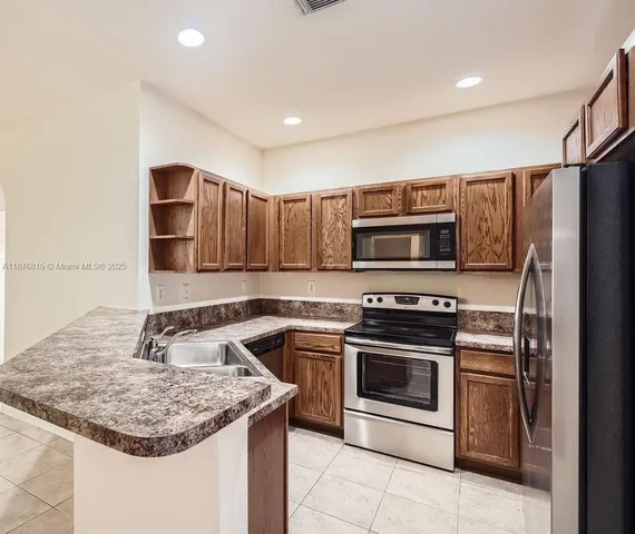 a kitchen with stainless steel appliances granite countertop a sink stove and refrigerator