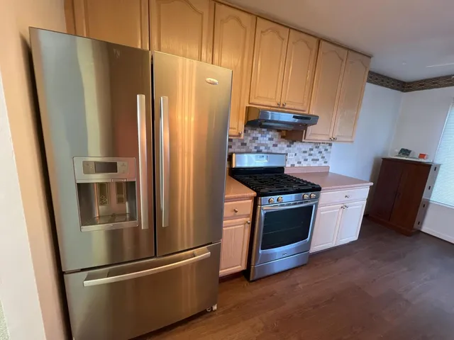 a kitchen with stainless steel appliances granite countertop a refrigerator a stove and a refrigerator