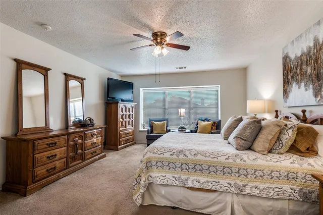 a bedroom with a bed a dresser and flat screen tv