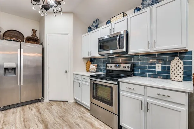 a kitchen with stainless steel appliances granite countertop a refrigerator a microwave oven a sink dishwasher and a refrigerator with wooden floor