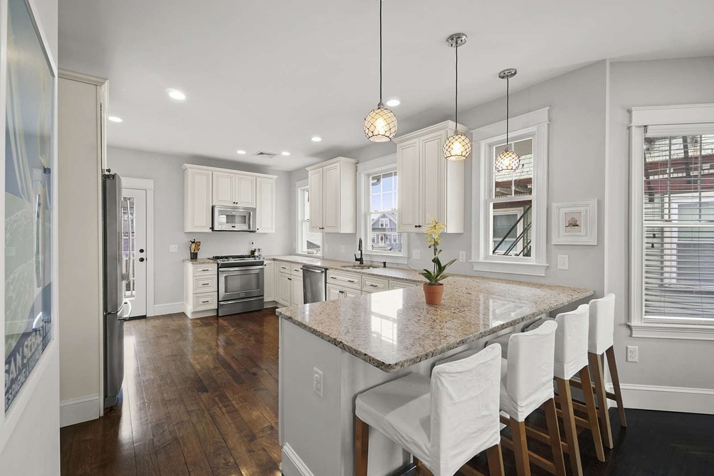 a kitchen with stainless steel appliances granite countertop a stove a sink refrigerator and a wooden floor