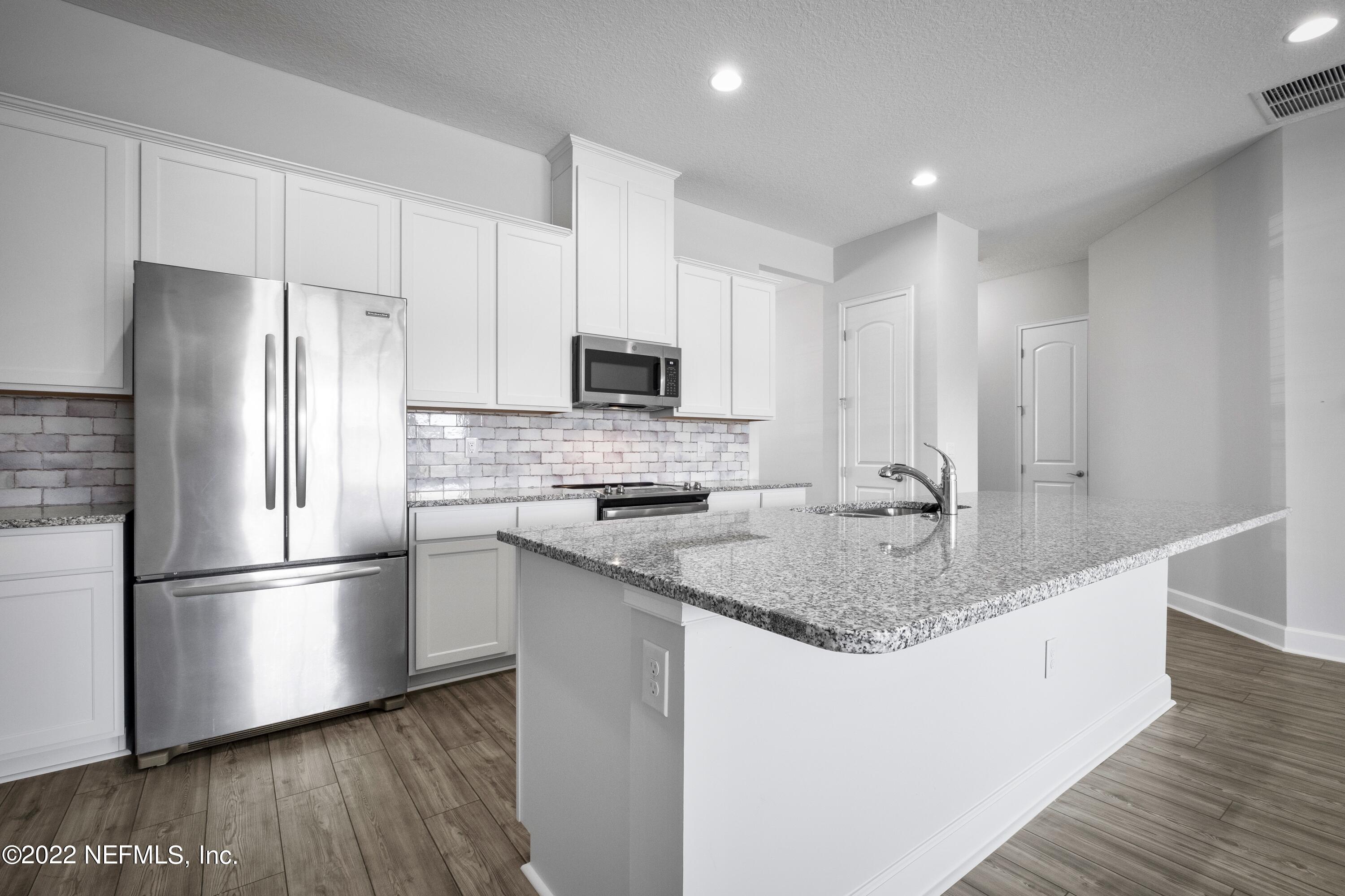 160 Daniel Creek Court St. Augustine, FL 32095 - Photo 18 of 35 a kitchen with stainless steel appliances granite countertop a refrigerator a sink a stove a microwave and wooden floors