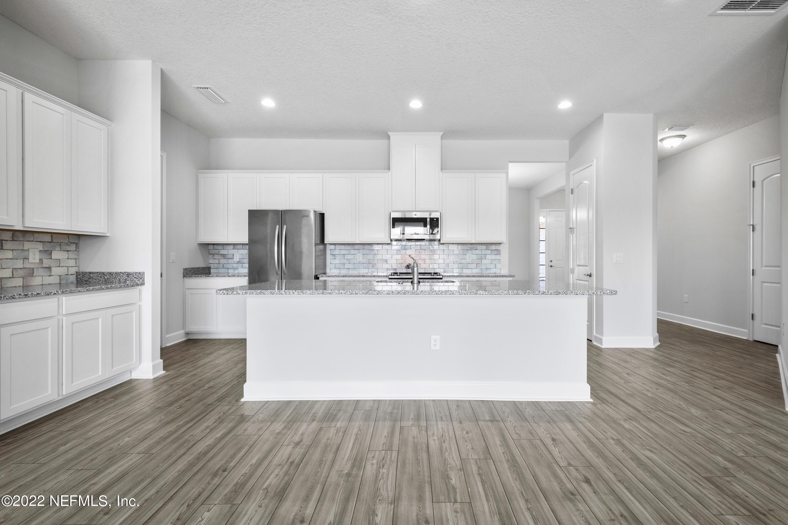 160 Daniel Creek Court St. Augustine, FL 32095 - Photo 3 of 35 a view of kitchen with stainless steel appliances granite countertop a stove a sink and white cabinets with wooden floor