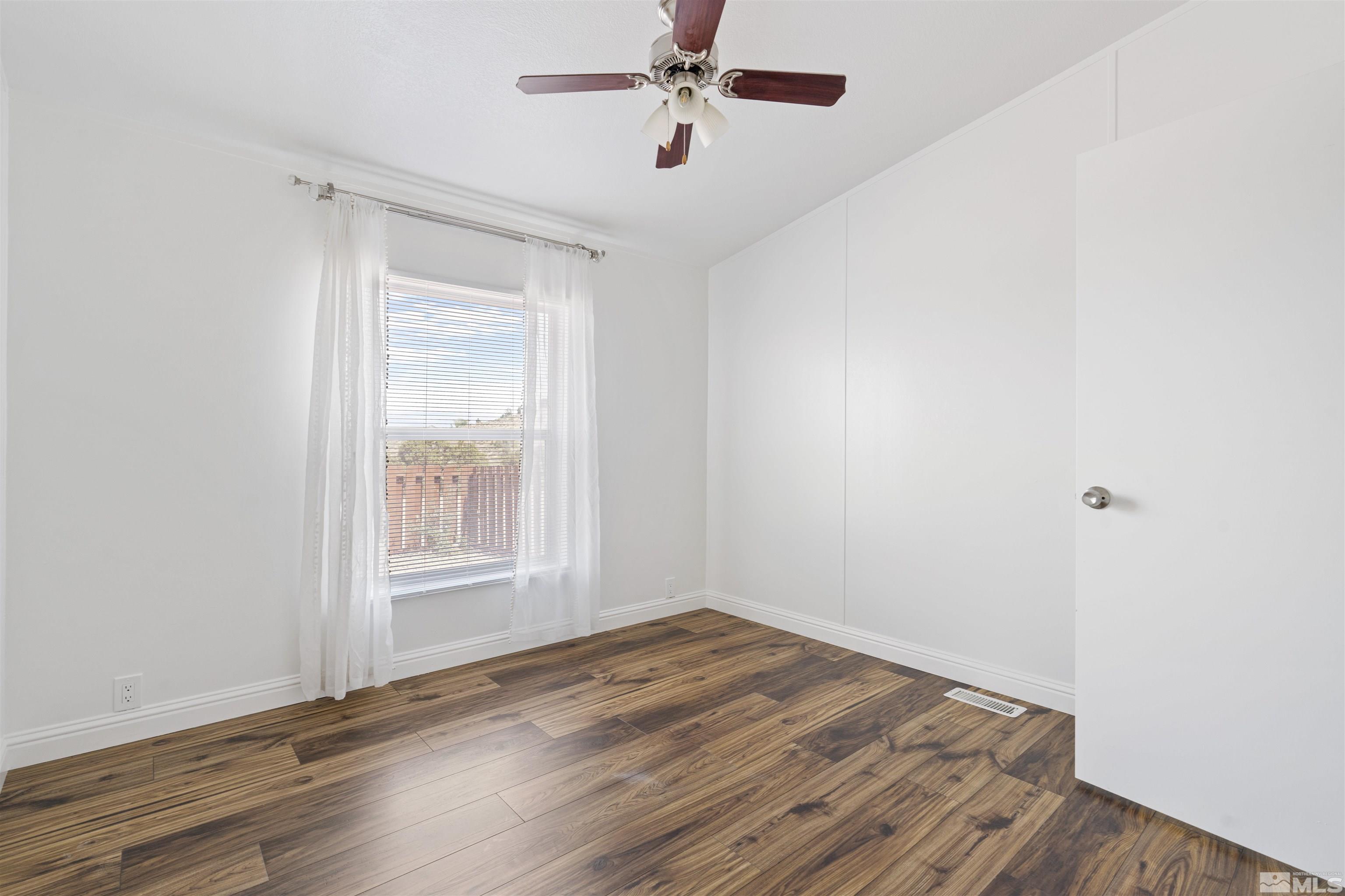 16000 Perlite Drive Reno, NV 89521 - Photo 15 of 29 an empty room with wooden floor ceiling fan and windows