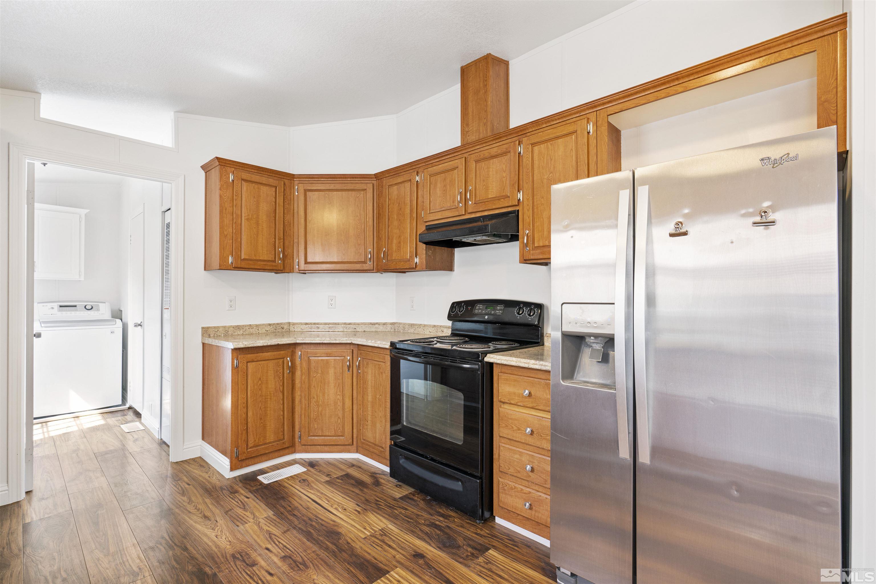 16000 Perlite Drive Reno, NV 89521 - Photo 7 of 29 a kitchen with a refrigerator a stove and a wooden floor