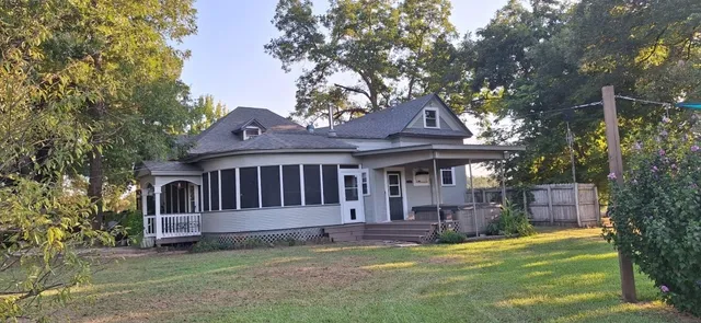a view of a house with a small yard and a large tree