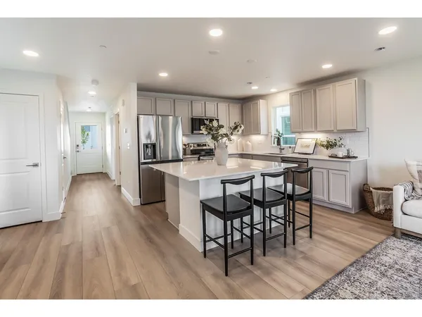 a kitchen with stainless steel appliances kitchen island granite countertop a table chairs sink and cabinets