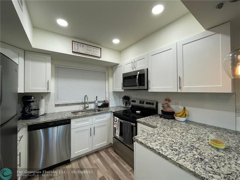 a kitchen with stainless steel appliances granite countertop a sink a stove and cabinets