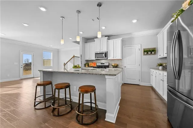 a kitchen with stainless steel appliances granite countertop a sink a stove a refrigerator cabinets and chairs