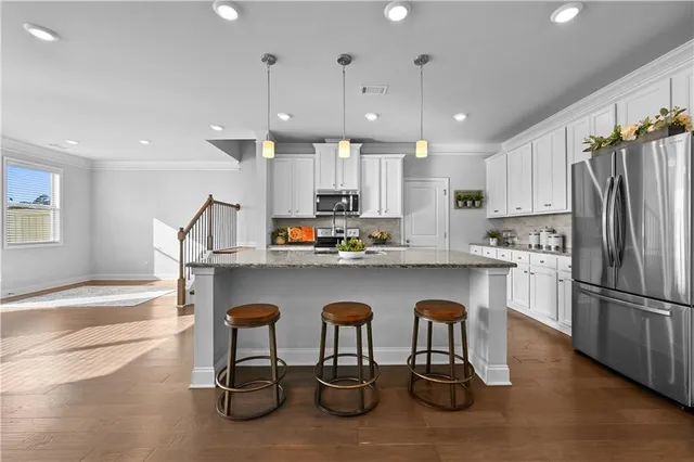 a kitchen with stainless steel appliances granite countertop a table chairs sink and refrigerator