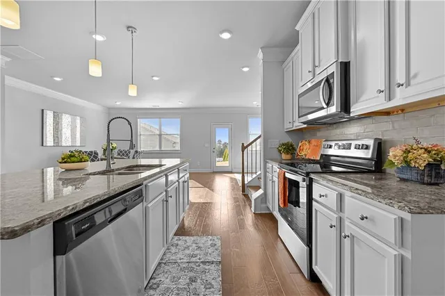 a large kitchen with stainless steel appliances granite countertop a lot of counter space and wooden floor