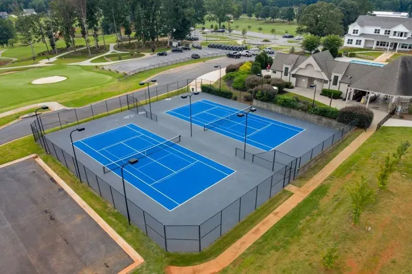 a view of a tennis court with a swimming pool and outdoor seating