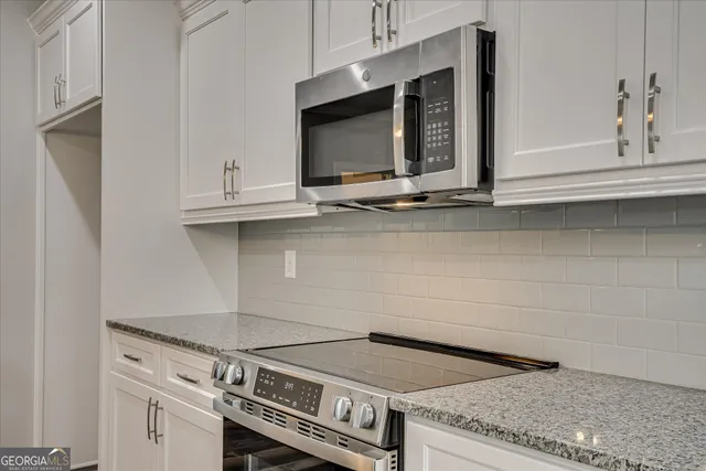 a kitchen with granite countertop a sink a counter top space cabinets and stainless steel appliances