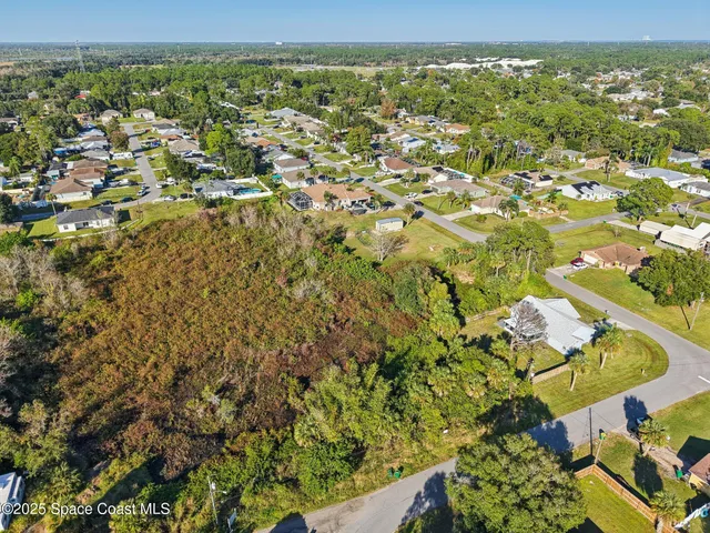 an aerial view of a houses with a yard and mountain