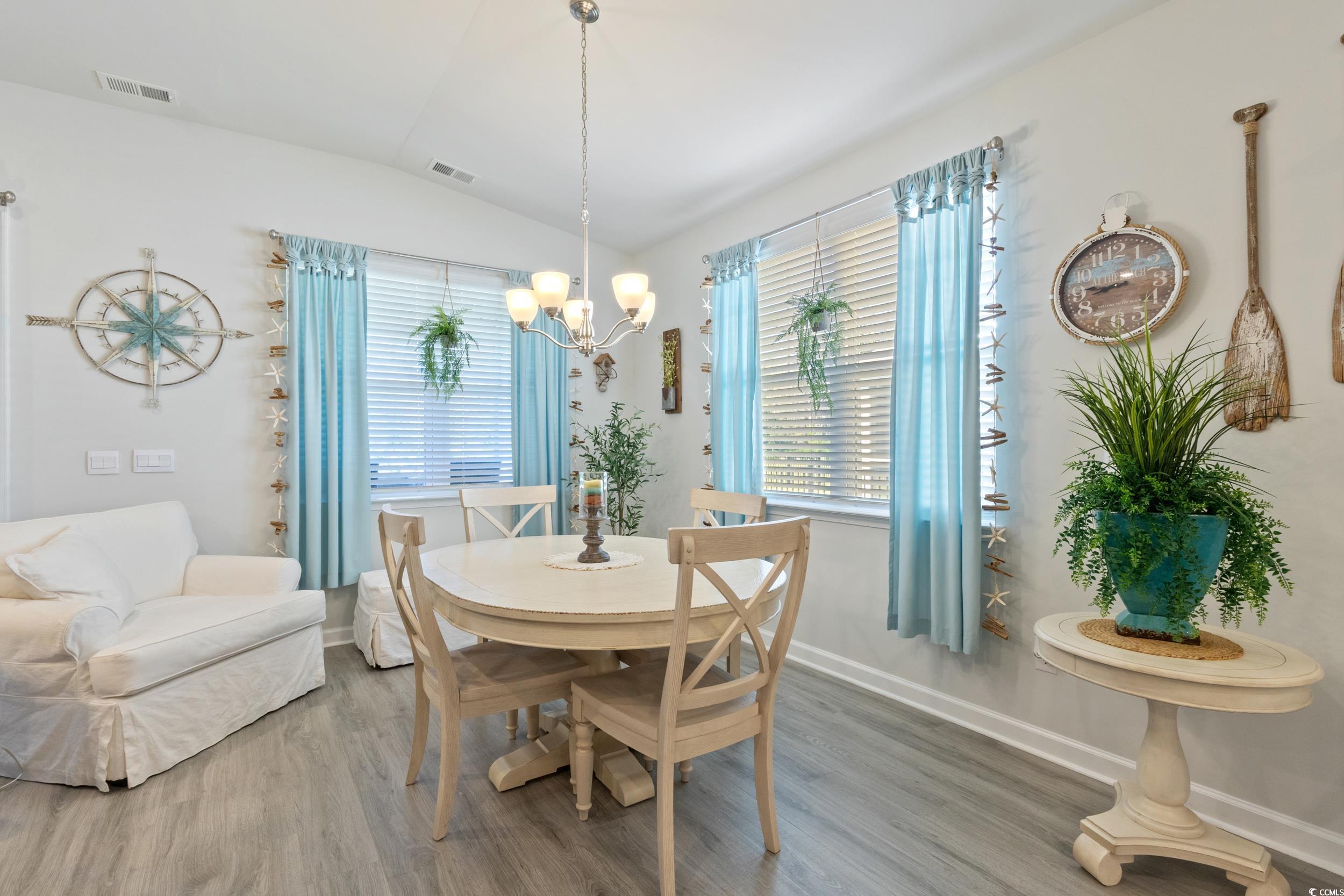 6037 Mcclain Court Little River, SC 29566 - Photo 13 of 39 Dining space featuring lofted ceiling, wood finished floors, and a chandelier