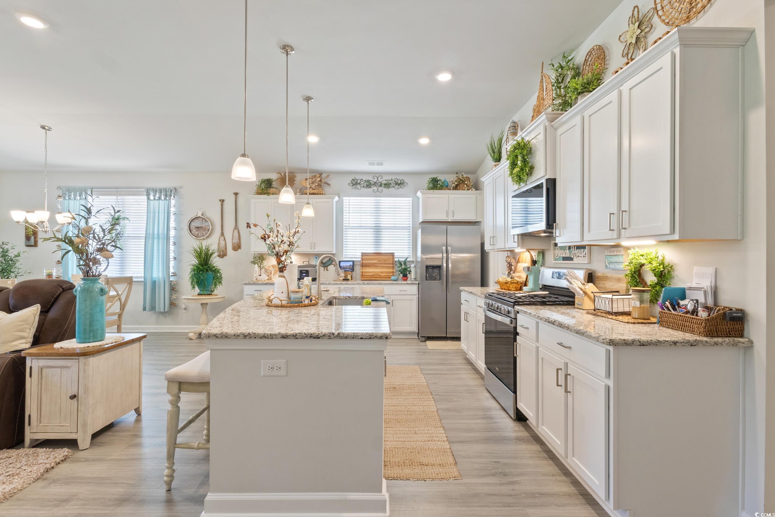 6037 Mcclain Court Little River, SC 29566 - Photo 14 of 39 Kitchen featuring a breakfast bar, appliances with stainless steel finishes, white cabinetry, recessed lighting, and light stone countertops