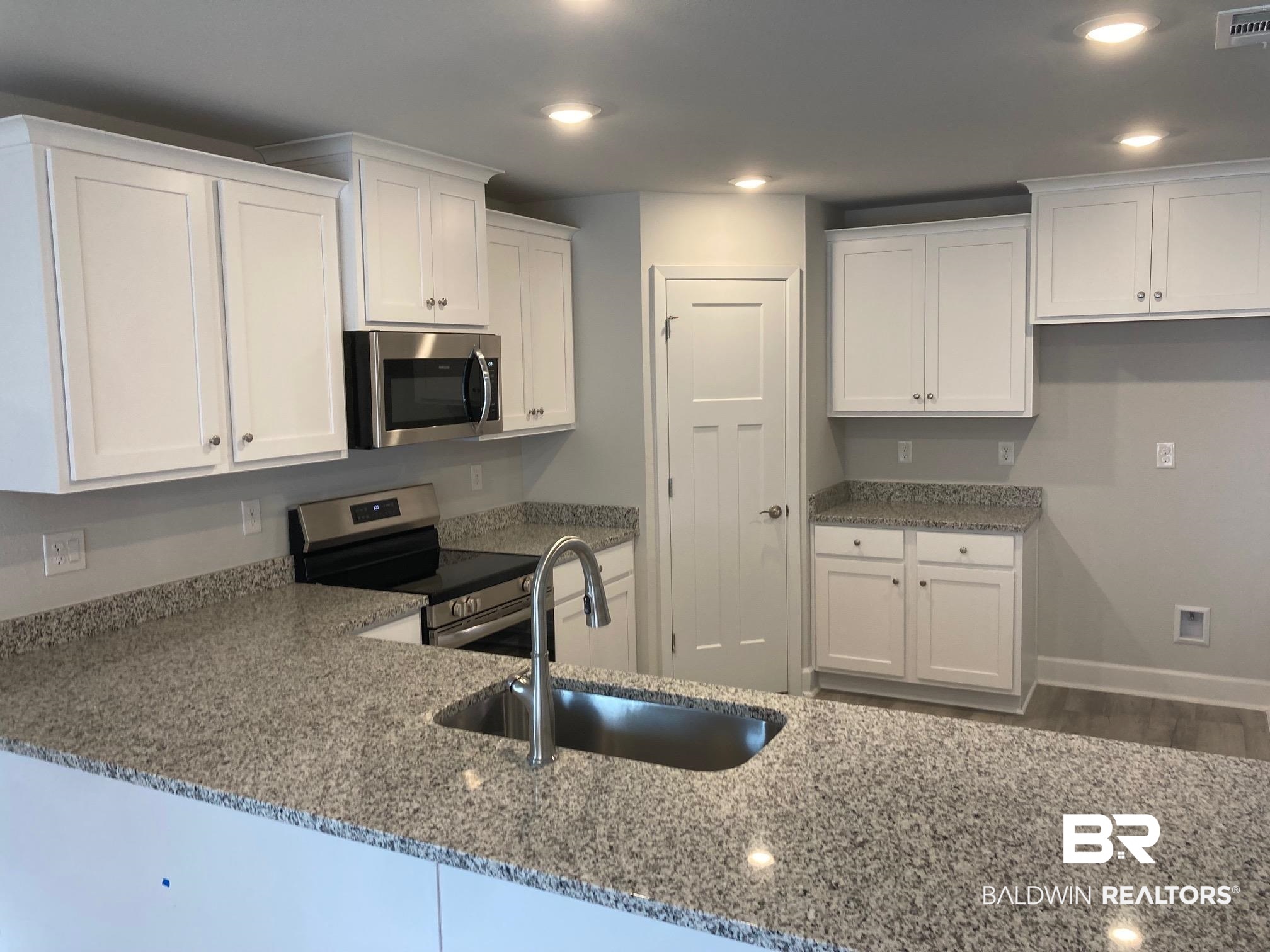705 Mayflower Drive Foley, AL 36535 - Photo 5 of 19 Kitchen featuring stone countertops, white cabinetry, a sink, and stainless steel appliances