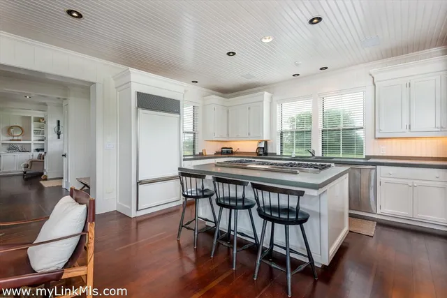 a kitchen with granite countertop a table chairs stove and wooden floor