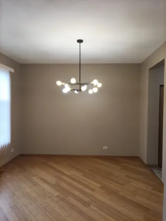 an empty room with chandelier fan and windows