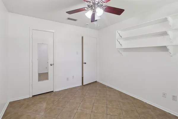 an empty room with windows and fan