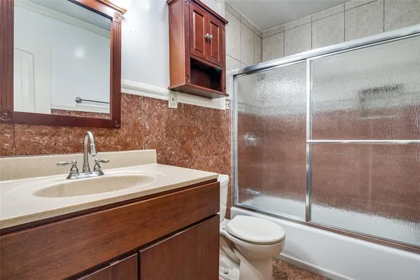 a bathroom with a granite countertop sink a toilet and a shower