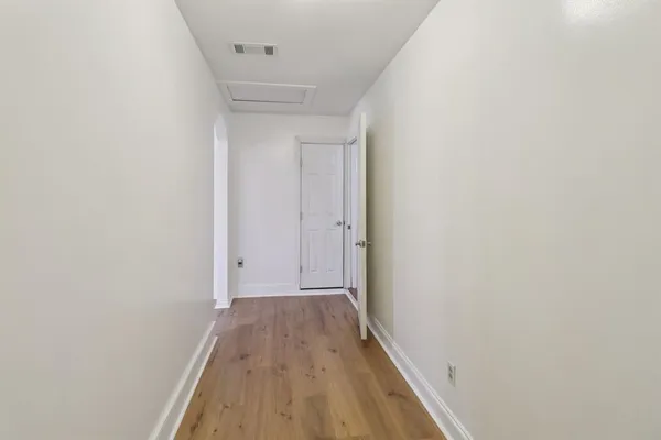an empty room with wooden floor chandelier fan and windows