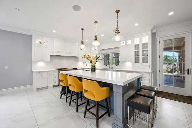 a kitchen with kitchen island granite countertop a table chairs sink and cabinets
