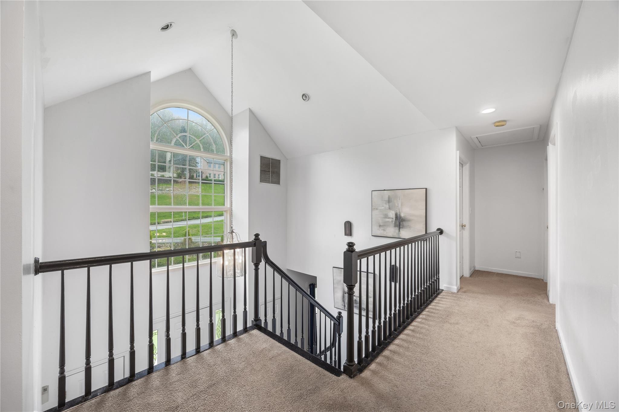 3 Miller Road Putnam Valley, NY 10579 - Photo 21 of 48 Vaulted ceiling entryway featuring a large arched window with grid details, a black wood baluster railing, recessed lighting, and carpeted flooring