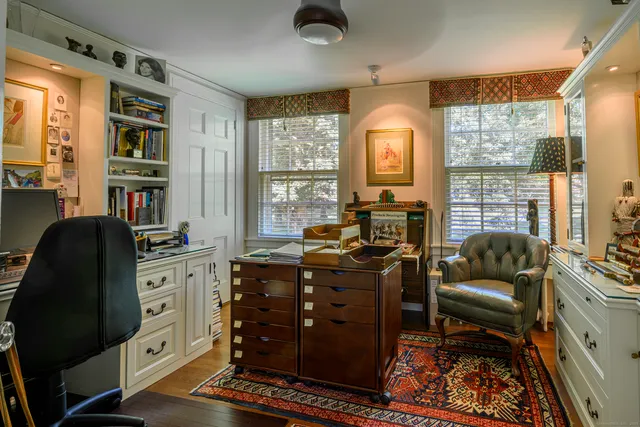 a view of a workspace with furniture and a large window