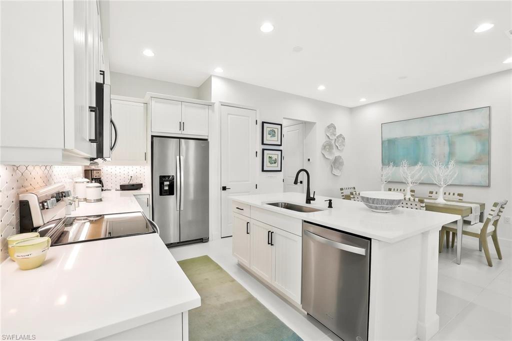 7295 Cayo Coco Lane Naples, FL 34113 - Photo 5 of 16 a large white kitchen with a stove a sink a refrigerator and a dining table with wooden floor