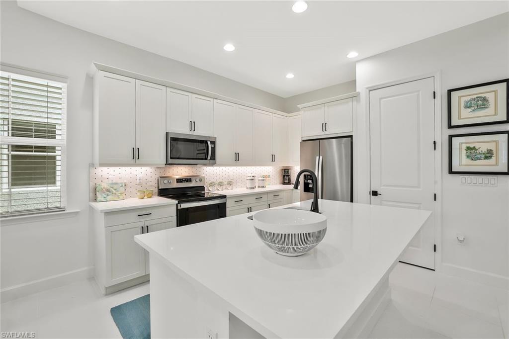 7295 Cayo Coco Lane Naples, FL 34113 - Photo 6 of 16 a kitchen with a refrigerator a stove top oven a sink dishwasher and a refrigerator with wooden floor