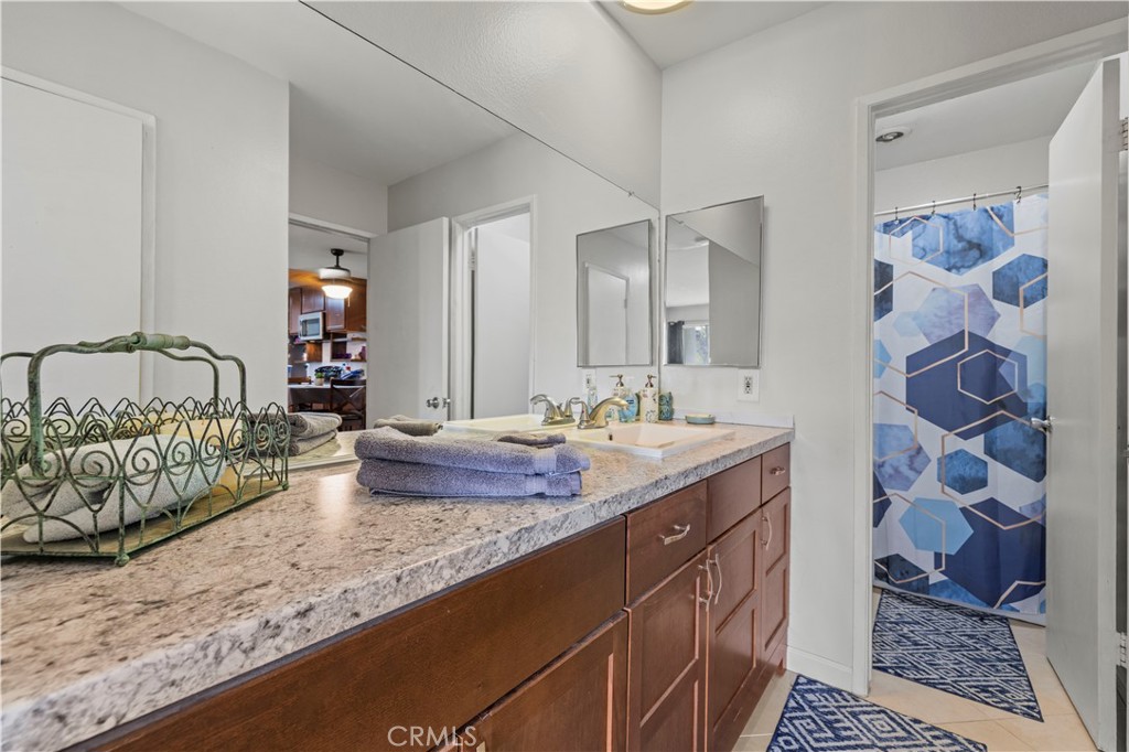 23515 Lyons Avenue, Unit 277 Valencia, CA 91355 - Photo 16 of 29 a bathroom with a granite countertop sink and a mirror