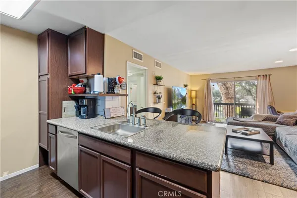 a kitchen with granite countertop kitchen island stainless steel appliances a sink stove and cabinets