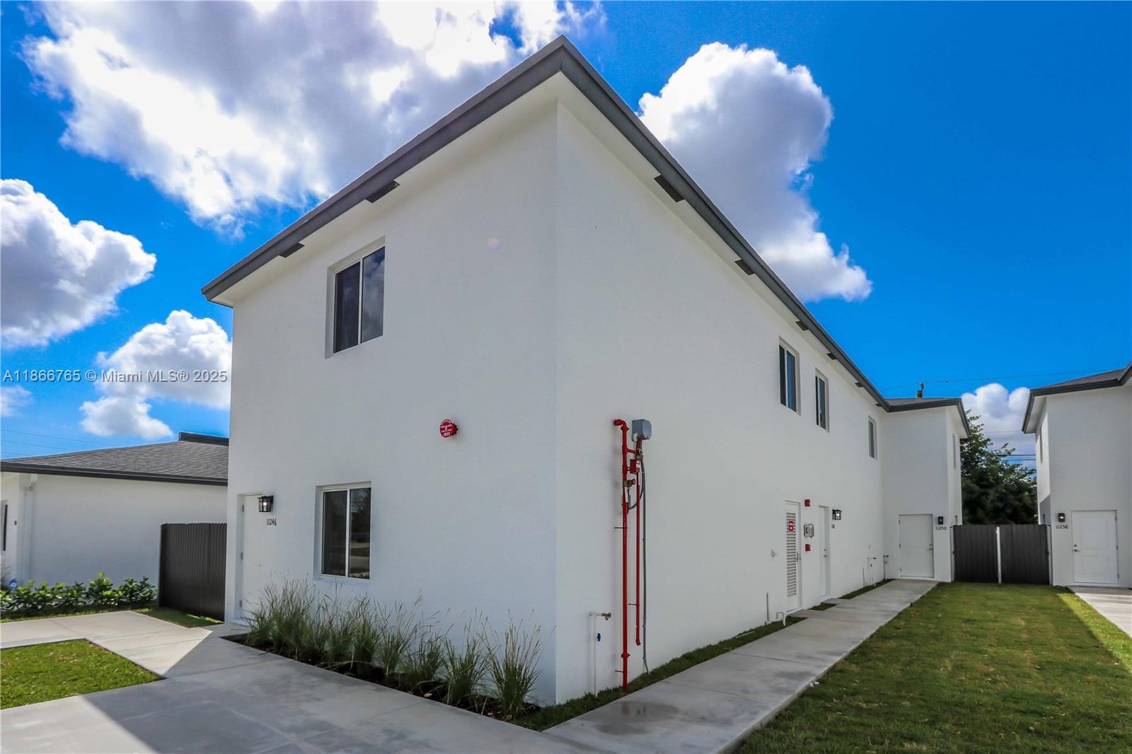 a view of a white house with a yard and a large tree