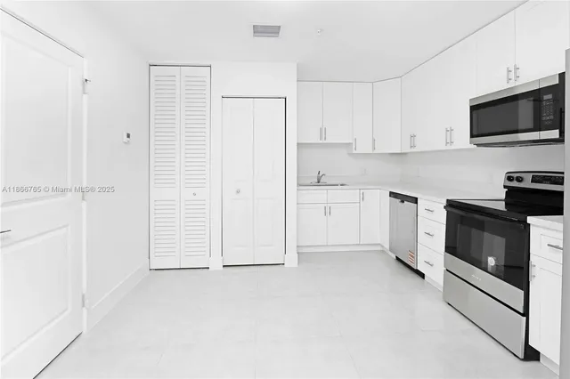 a view of a kitchen with white cabinets and stainless steel appliances