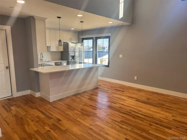 a large kitchen with stainless steel appliances a large counter top a stove and a refrigerator