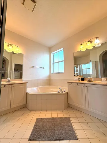 a bathroom with a tub a sink a mirror and a shower