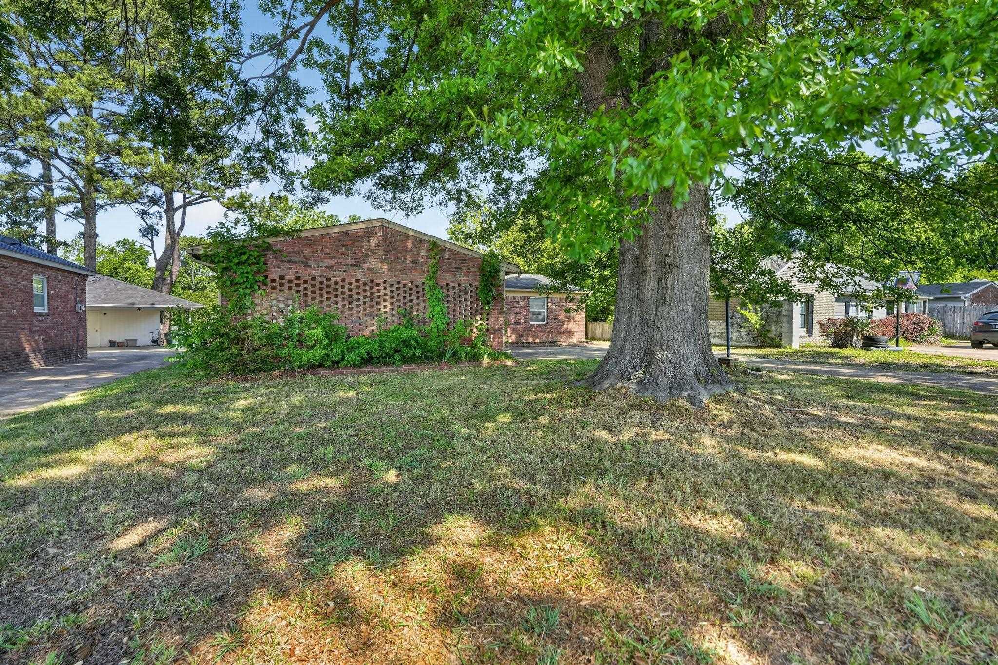 3445 Powers Road Memphis, TN 38128 - Photo 2 of 35 Expansive front yard featuring a mature shade tree and a brick structure with decorative lattice work