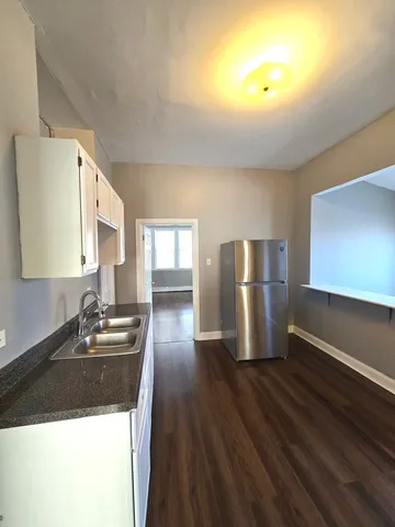 a kitchen with stainless steel appliances granite countertop a refrigerator a sink dishwasher a stove and white countertops with wooden floor