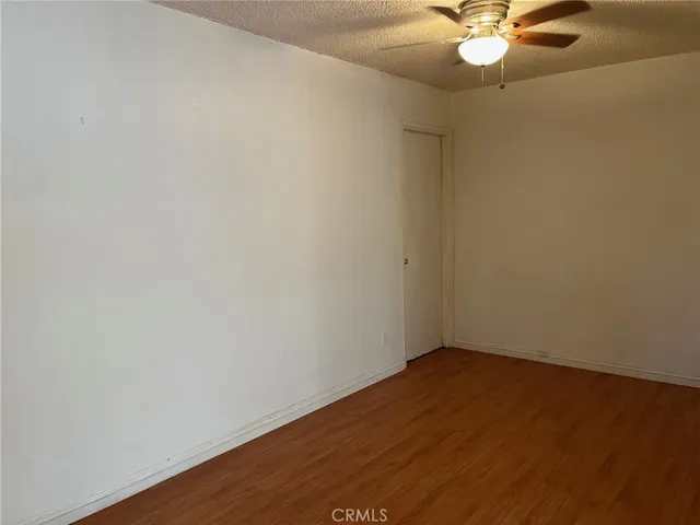 an empty room with a chandelier fan and wooden floor