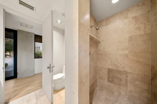 a spacious bedroom with a bed a table and a large mirror next to a window