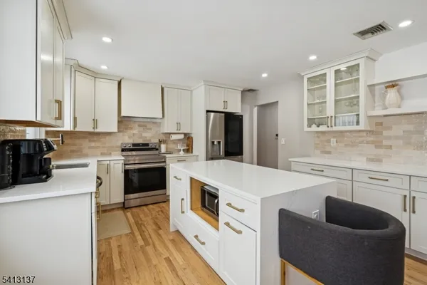 a kitchen with stainless steel appliances white cabinets a sink a stove a refrigerator and a stove