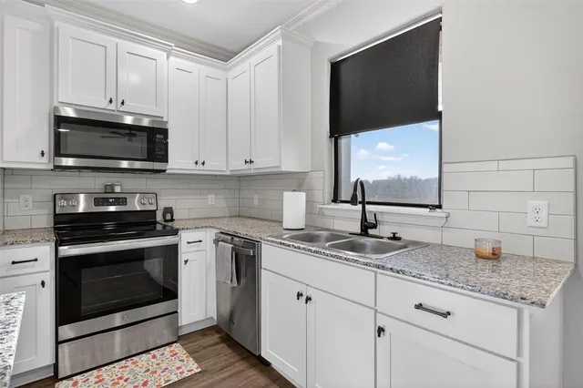 a kitchen with granite countertop white cabinets stainless steel appliances and a sink