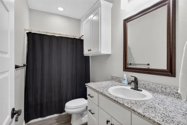 a bathroom with a granite countertop sink toilet and a mirror