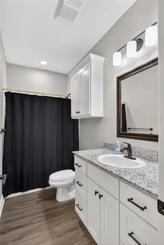 a bathroom with a granite countertop sink toilet and mirror